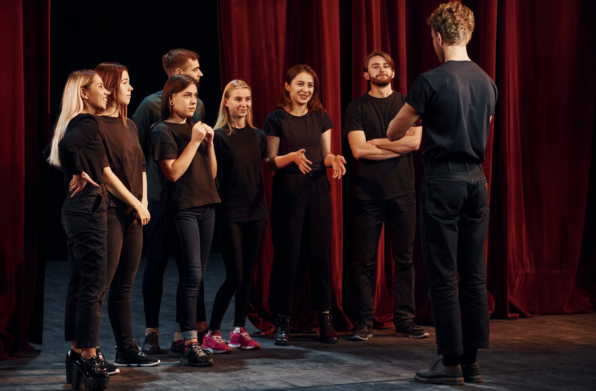 Group of actors in dark colored clothes on rehearsal in the theater